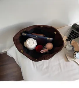 Intérieur spacieux du sac cabas en daim marron foncé contenant une tablette et un portefeuille