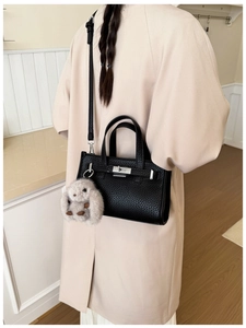 Close-up of black litchi pattern leather tote bag featuring silver lock and plush rabbit charm