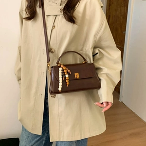 Détail du sac à bandoulière vintage en cuir marron avec gland en perles de bois et fermoir doré