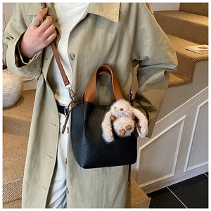 Sac seau en cuir noir chic avec poignées marron et un charmant lapin en peluche blanc