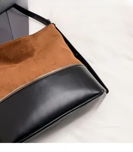 Detail of two-tone bucket bag with brown suede and black leather stitching