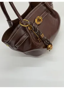 Detailed view of dark brown leather dumpling bag with gold lock and metal key charm