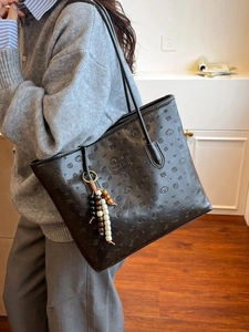 Black PU tote bag with dog pattern embossing and beaded charm shown on shoulder