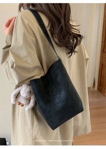 Minimalist black suede bucket bag with plush rabbit pendant shown from a back view on a model