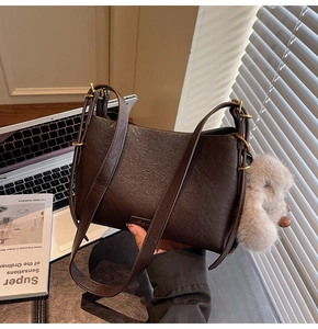 Close-up of dark brown leather handbag texture with gold hardware and gray plush ball