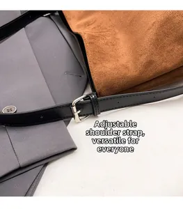 Detail of adjustable black leather strap on a brown suede bucket bag for women