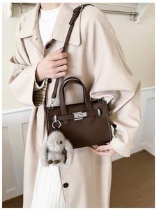 Detail of dark brown lychee leather handbag with silver lock and plush bunny charm