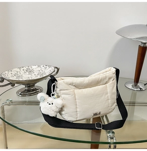 Vue détaillée du sac bandoulière matelassé avec sangle en nylon et porte-clé ours en peluche