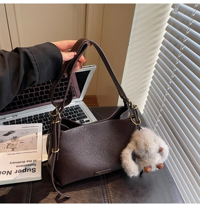 Detailed view of dark brown pebbled leather handbag with cute plush bunny charm accessory