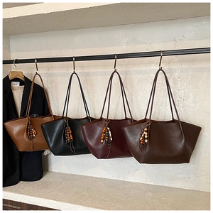 Close-up of vintage tote bags in brown, black and burgundy with wood bead tassels