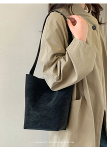 Black matte shoulder bucket bag with wide strap styled with a beige trench coat
