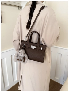 Detail of dark brown lychee leather tote with silver buckle and rabbit charm pendant