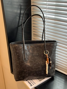 Black leather tote bag with embossed puppy pattern and colorful wooden bead accessory