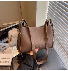 Detail of brown litchi pattern leather tote bag with gold rings and plush bear charm