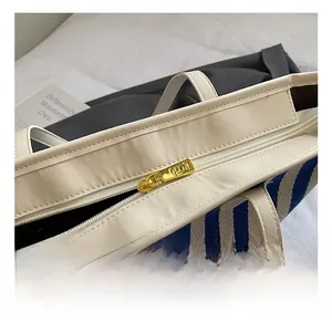 Detail view of golden zipper closure on blue and white striped woven tote bag