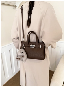 Detail of dark brown pebble leather tote bag with silver lock and plush bunny charm