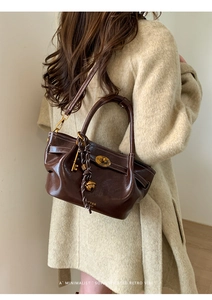 Detail of dark brown glossy leather handbag with vintage twist lock and key pendant