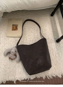 Close-up of deep brown vintage tote bag with cute plush rabbit charm on a white rug