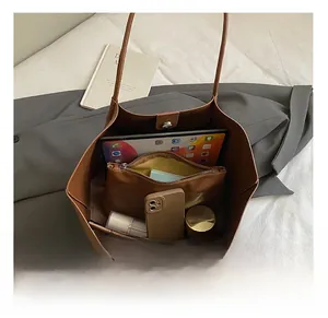 Internal storage view of brown leather tote showing space for tablet and makeup