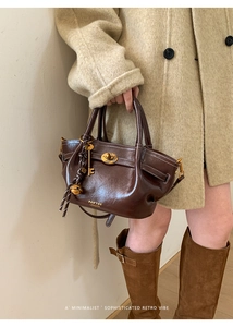 Detail of dark brown leather bucket bag featuring gold hardware and logo on bottom