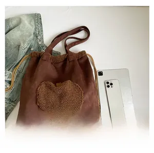 Dettaglio della borsa tote in pelle scamosciata con mela in peluche e chiusura a lacci