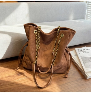 Détail du sac cabas en daim marron avec matelassage en losange et chaîne dorée