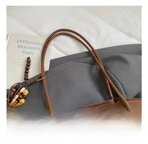 Close-up of brown faux leather tote bag handle and ethnic wooden bead charm detail