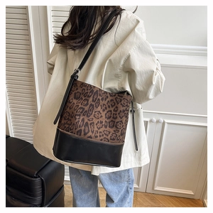 Detail of leopard print bucket bag with black leather bottom worn by a model