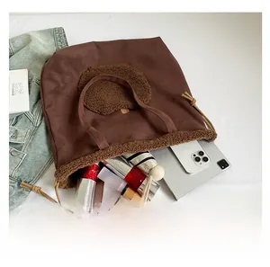 Dettaglio della grande capacità della borsa tote in pelle scamosciata marrone con orsetto