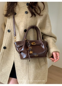Detail of dark brown leather bucket bag with retro metal lock and brand logo print