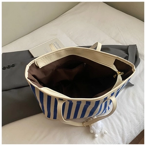 Detailed interior of blue striped canvas tote bag with zipper pocket and leather handle