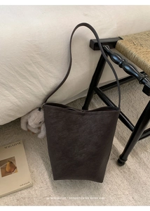 Close-up of retro bucket bag in dark grey matte leather with a cute plush rabbit charm