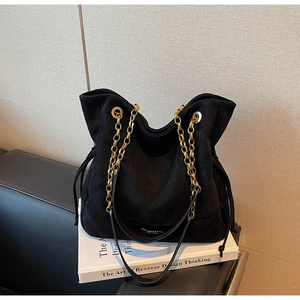 Détail du sac cabas en daim avec bandoulière en chaîne dorée et lettrage de marque