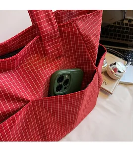 Détail du cabas à carreaux rouges montrant une poche latérale pour grands téléphones