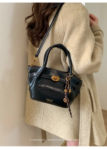 Detail of black glossy leather tote bag featuring contrast stitching and gold twist lock