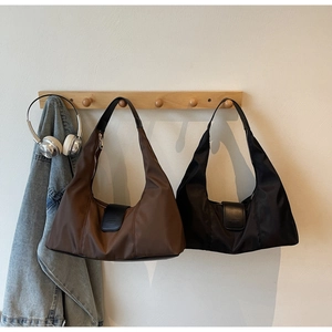 Detail of brown and black nylon crescent shoulder bags on a minimalist wooden rack