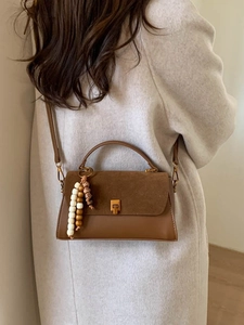 Sac à bandoulière en cuir marron avec breloque perlée présenté sur le dos d'un mannequin