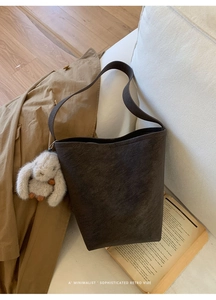 Detail of retro dark brown leather bucket bag with cute rabbit charm and shoulder strap