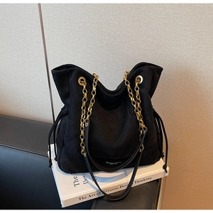 Détail du sac cabas en daim noir avec chaînes dorées et cordons de serrage latéraux