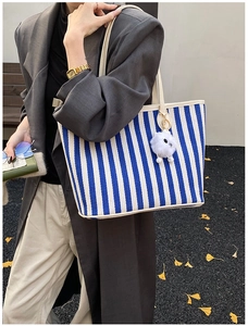 Detailed texture of blue and white striped canvas tote bag with white faux fur pompom charm