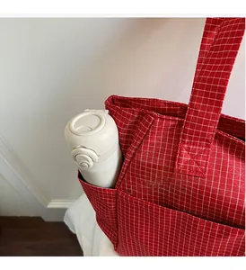 Détail du sac cabas à carreaux rouges montrant la poche latérale et la grande capacité