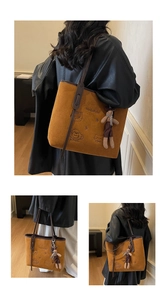 Close-up of brown suede tote bag featuring cartoon embroidery and soft rabbit plush charm