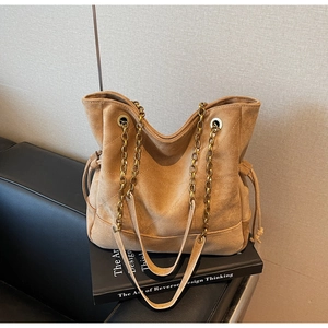Détail du sac cabas en daim camel avec coutures en V et bandoulière chaîne dorée
