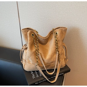 Détail du sac cabas en daim camel avec coutures en losange et bandoulière en chaîne dorée