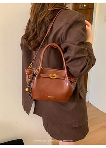 Detail of vintage brown leather bucket bag with gold twist lock and woven charm