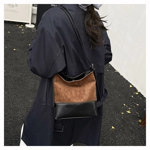 Detail of minimalist bucket bag with brown suede and black leather patchwork design