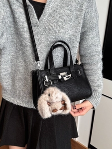 Classic black leather tote bag with silver hardware and cute rabbit charm on a model