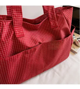Gros plan sur un cabas à carreaux rouges avec plusieurs poches en toile de nylon douce