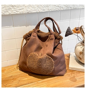 Detail of plush heart-shaped shearling patchwork on brown faux suede tote bag