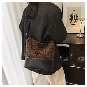 Detail view of large leopard print bucket bag with black leather patchwork and metal zipper